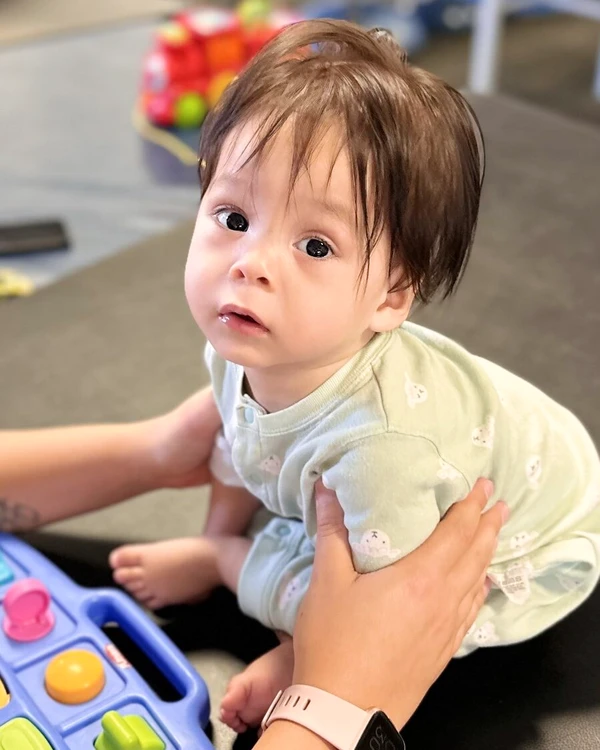 Physiotherapist doing a sensory exercise with a young child sitting in front of a toddler activity game