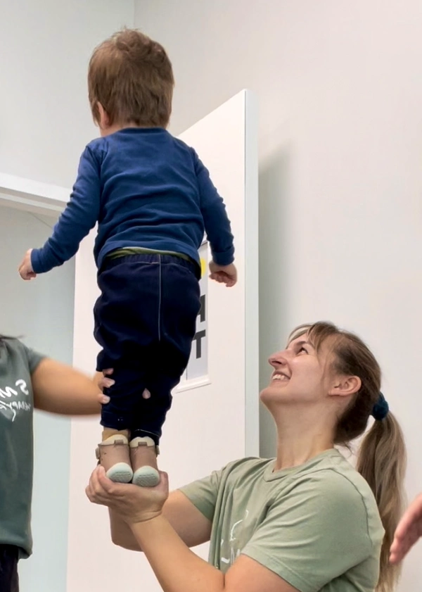 Physiotherapist holding and balancing young child with his feet on one hand