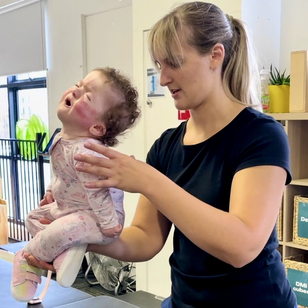 Physiotherapist holding and balancing young child on one hand