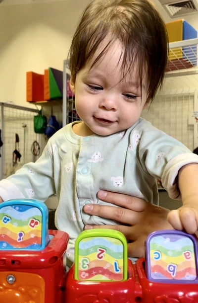 Smiling toddler playing with an activity game for letters, numbers and sounds